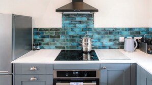 Una cucina moderna con frigorifero in acciaio inossidabile, cappa aspirante nera, piano cottura in vetro e forno integrato.