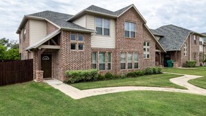 A two-story house with a brick exterior, a front porch, and a well-maintained lawn.