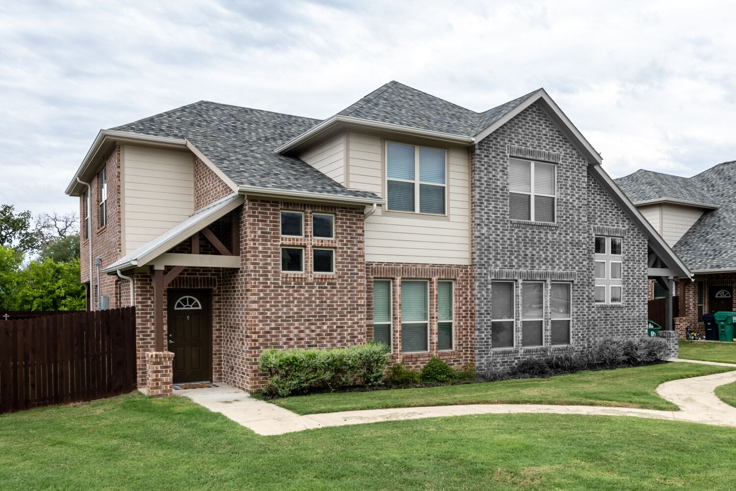 A two-story house with a brick facade and a grey roof.