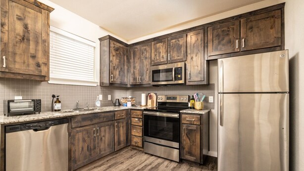 A kitchen with wooden cabinets, stainless steel appliances, a dishwasher, a microwave, an oven, and a refrigerator.