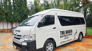 A white van with "The Haven Boutique Hotel Kumasi" branding parked on a stone-paved area. - The Haven (Ejisu)