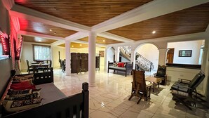 A spacious living area with a high ceiling, a staircase, and a dining area. - The Haven (Ejisu)