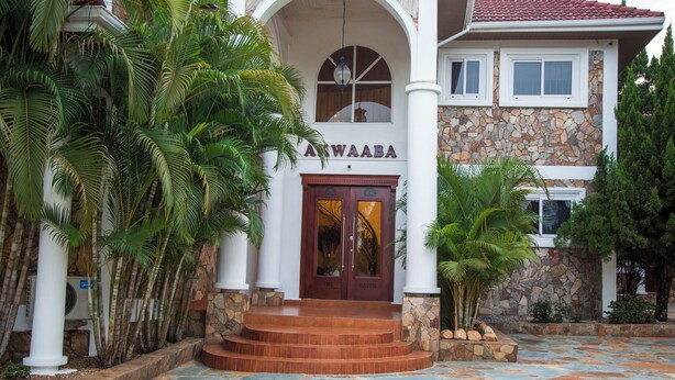 A building with a stone facade, a sign reading "Awaaba", and a tiled entrance area. - The Haven (Ejisu)