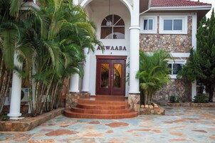 A building with a stone facade, a sign reading "Awaaba", and a tiled entrance area.