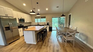 A modern kitchen with white cabinets, stainless steel appliances, and a wooden island.