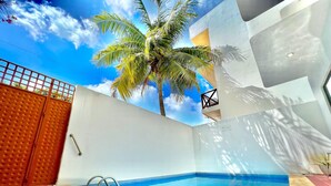 A swimming pool with a clear blue water, surrounded by a red brick patio. - Mid-Island Condo with Rooftop Balcony (Isla Mujeres)