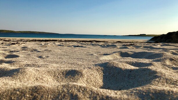 Una playa con cielo despejado y mar tranquilo.