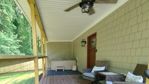 A covered porch with a ceiling fan, a hot tub, wicker furniture, and a view of the yard. - Cozy Haven  A Romantic Get-A-Way with HOT TUB (Denver)