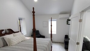 A bedroom with a four-poster bed, a ceiling fan, and a large window providing natural light. - Cozy Haven  A Romantic Get-A-Way with HOT TUB (Denver)