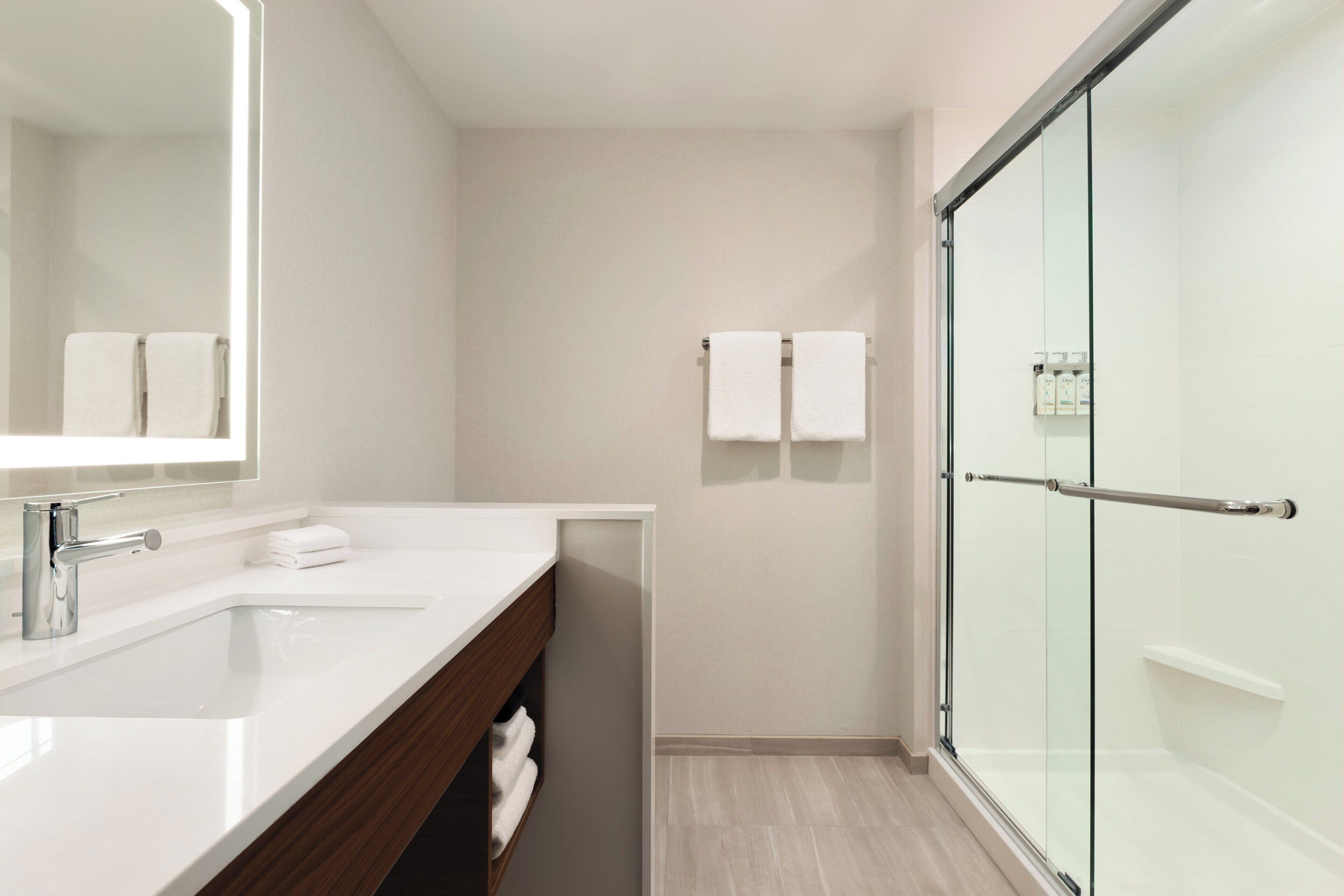 Un baño moderno con cabina de ducha de vidrio, un lavamanos blanco y un espejo.