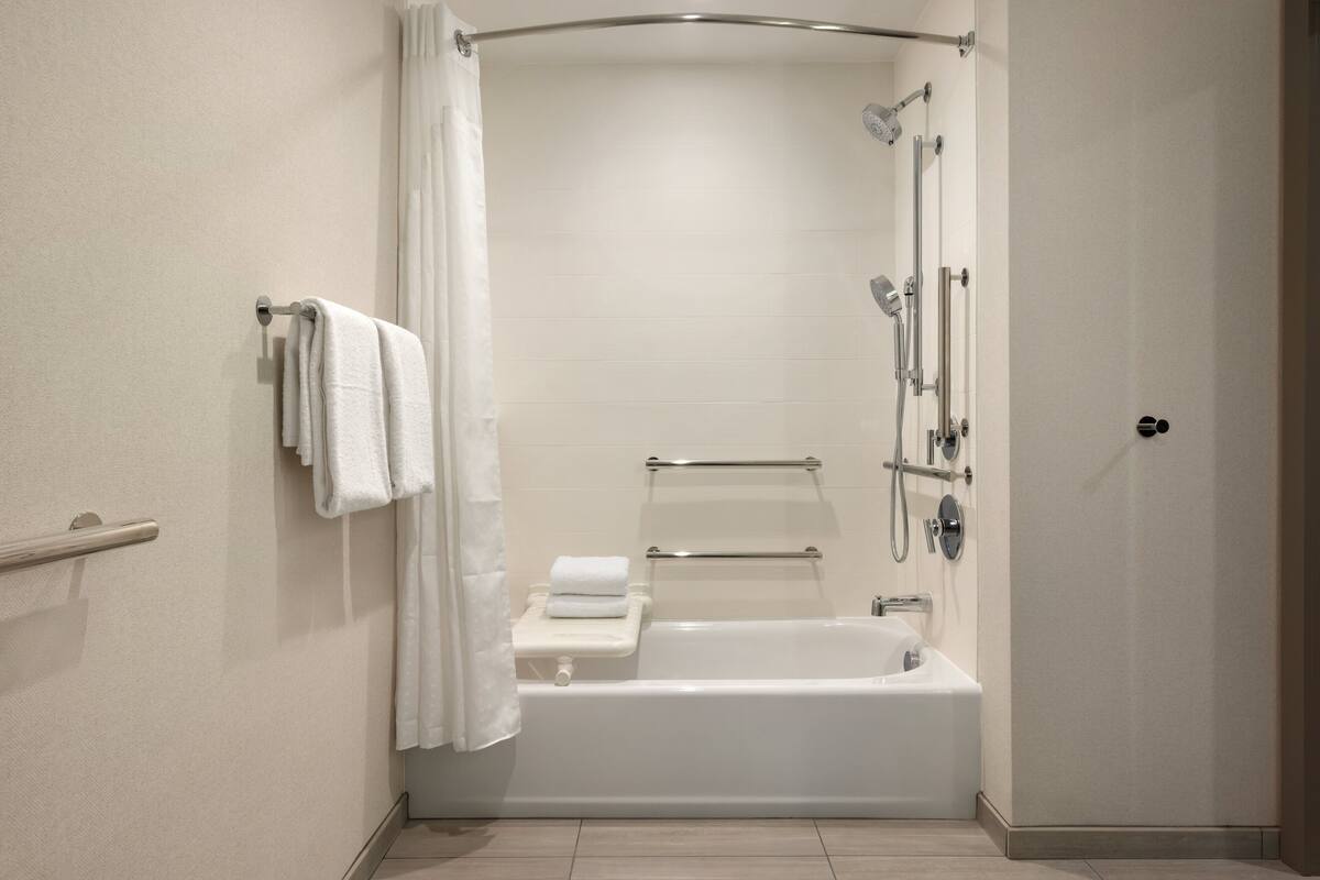 Un baño moderno con bañera, ducha y barras de apoyo.
