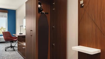 Una habitación con un armario de madera, una silla de oficina roja, un escritorio blanco y un estante pequeño blanco.