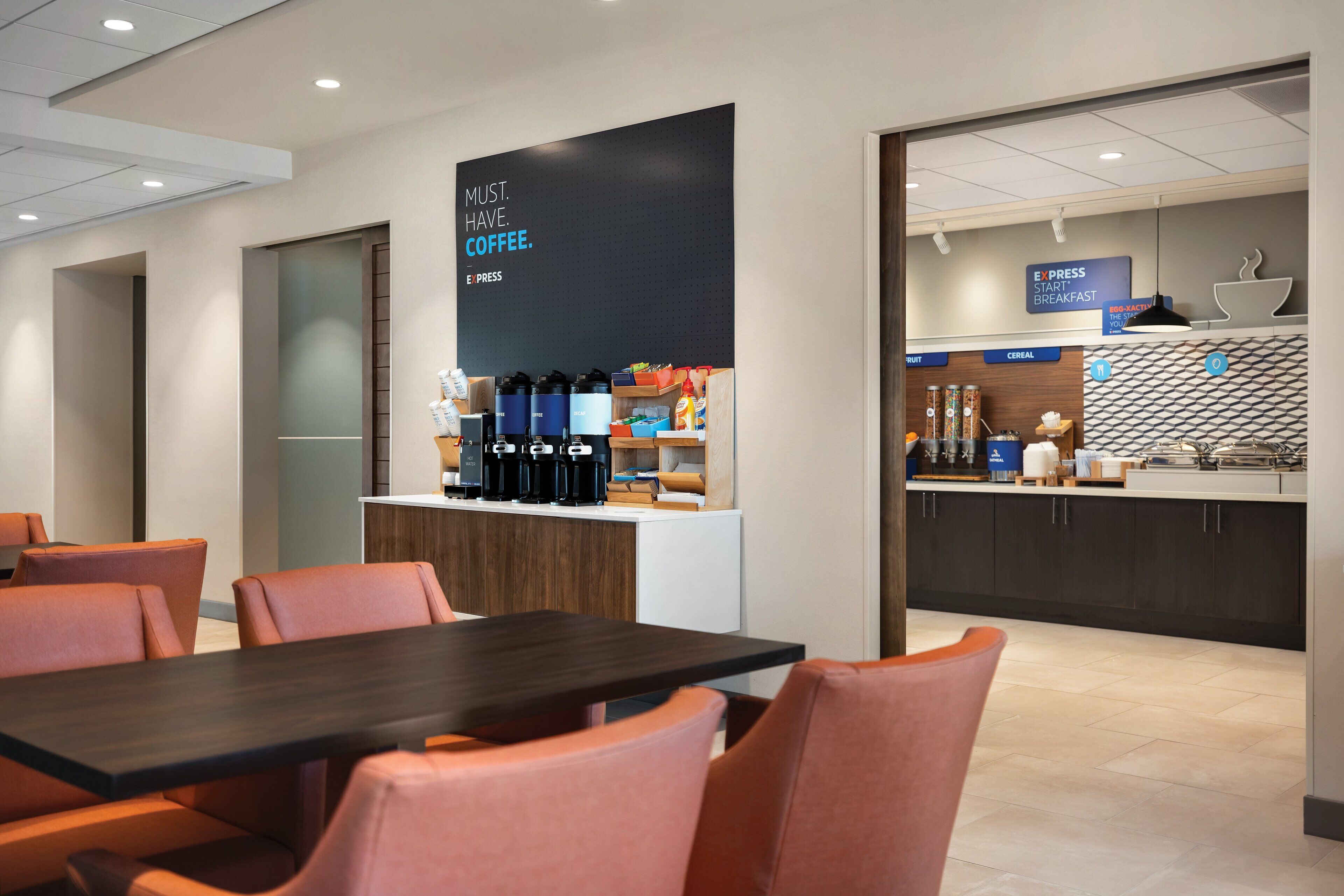 Un hall d’hôtel moderne doté d’un espace café, d’un coin salon et d’un buffet pour le petit-déjeuner.