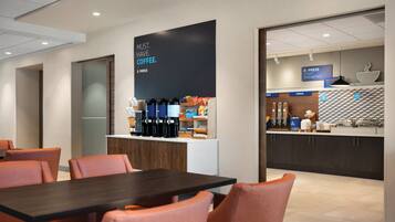 Un hall d’hôtel moderne doté d’un espace café, d’un coin salon et d’un buffet pour le petit-déjeuner.
