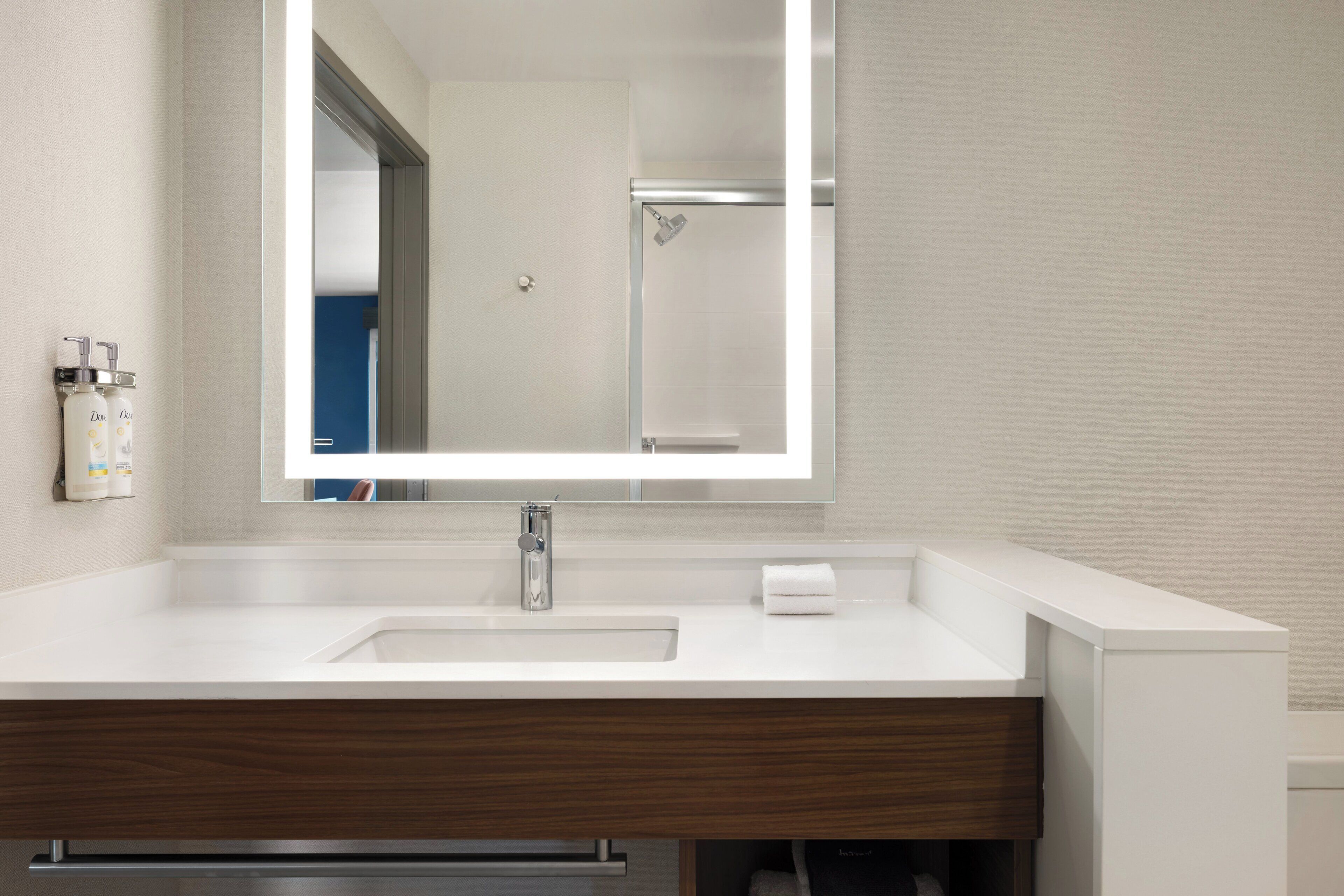 Un baño moderno con un espejo grande, un lavamanos blanco y un mueble de tocador de madera.