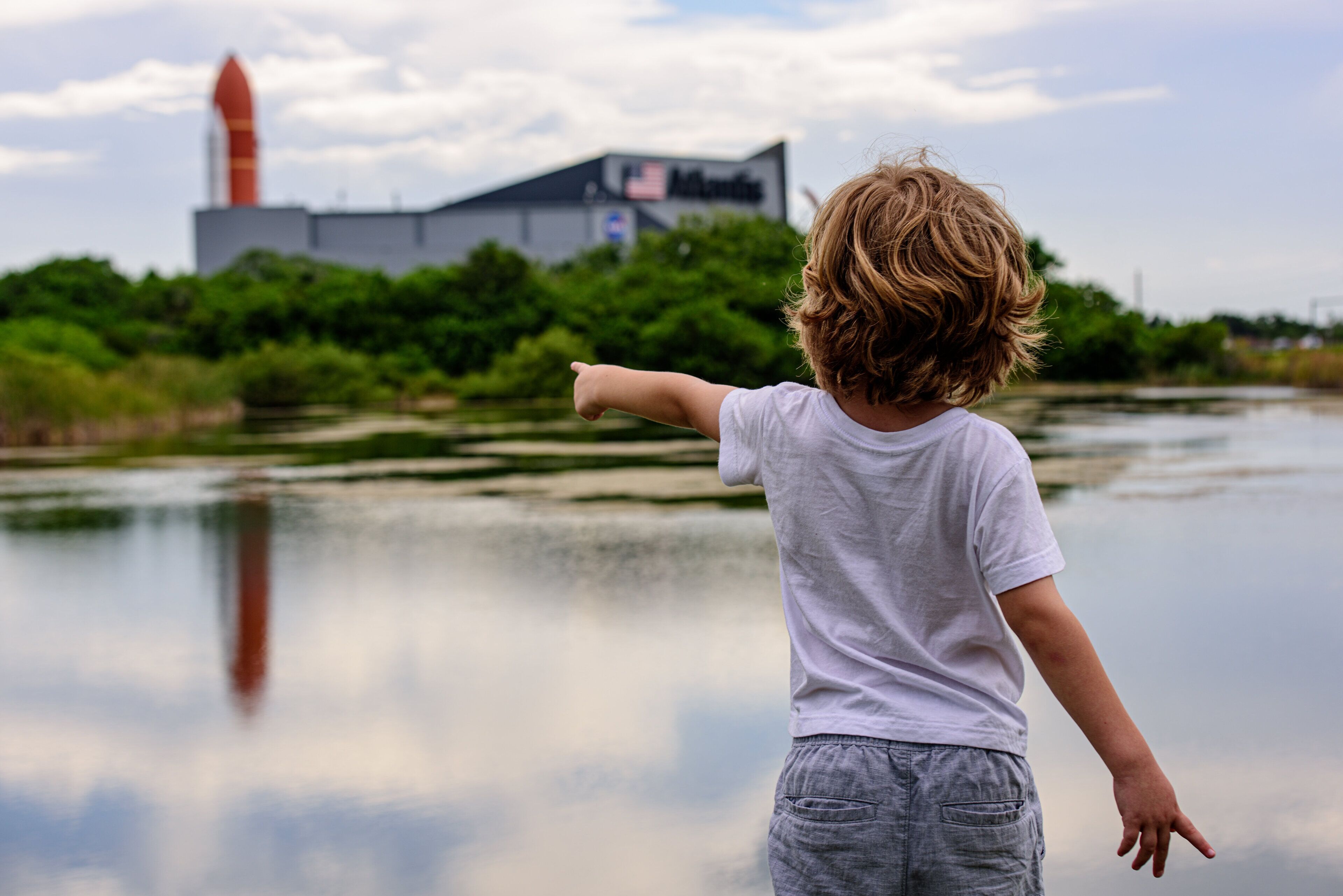 A child pointing towards a rocket launch facility.