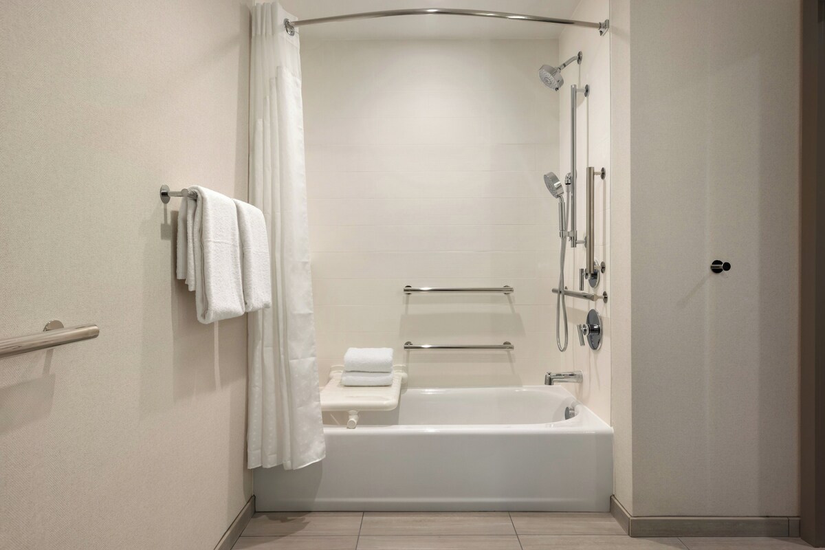 Ein modernes Badezimmer mit Badewanne, Dusche und Haltegriffen.
