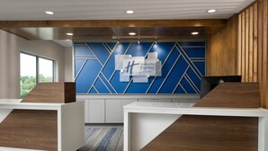 A reception area with a modern design, featuring a blue geometric wall, wooden accents, and a sign for Holiday Inn Express & Suites.
