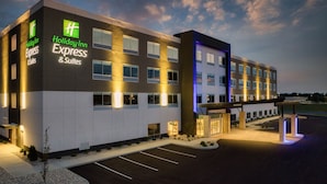 A Holiday Inn Express & Suites building with a modern design, featuring a parking lot and a landscaped area with small plants.