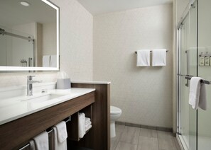 A modern bathroom with a glass shower enclosure, a white sink with a wooden vanity, and a toilet.