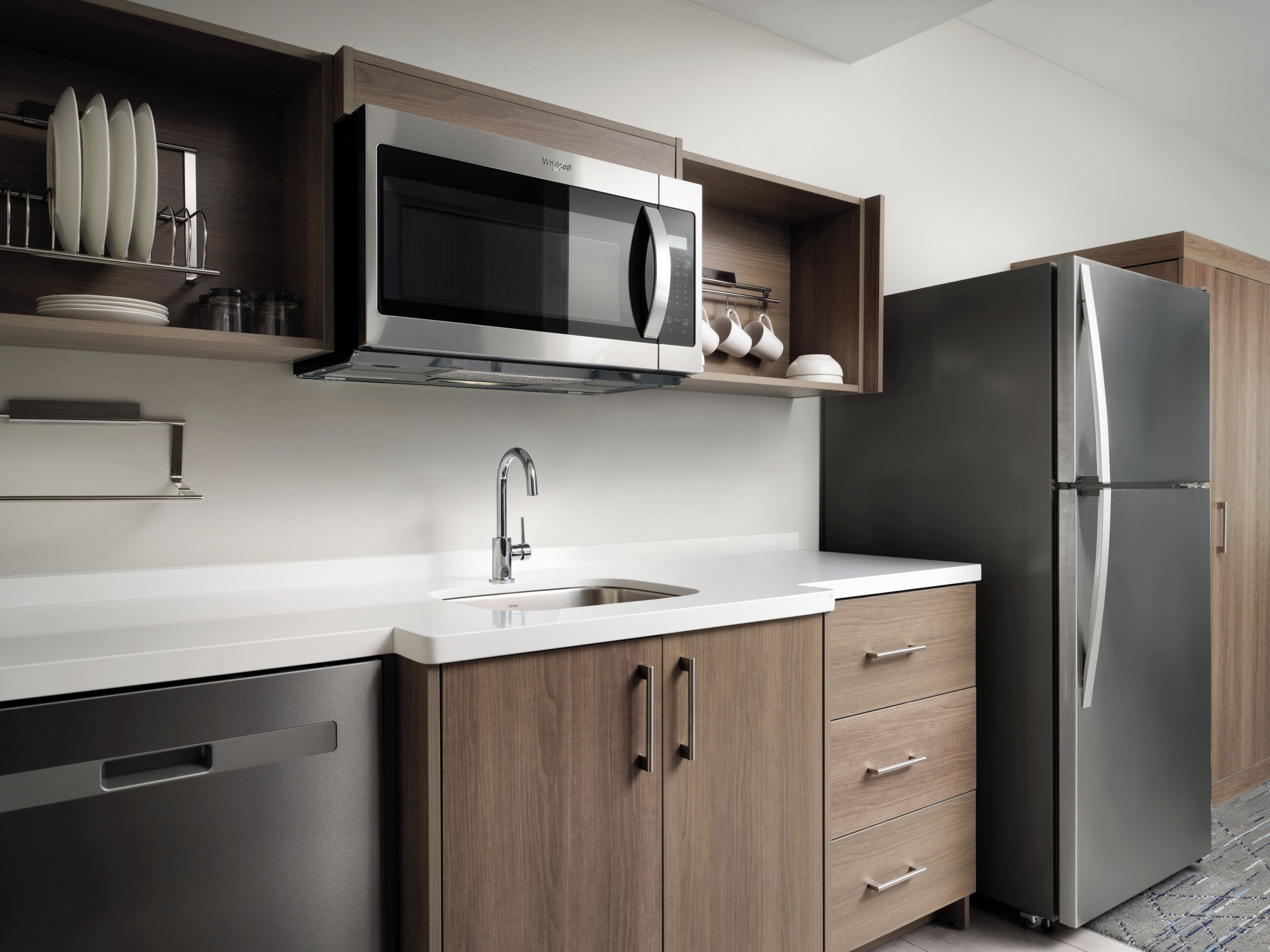 A modern kitchen with stainless steel appliances, wooden cabinets, and a built-in microwave.
