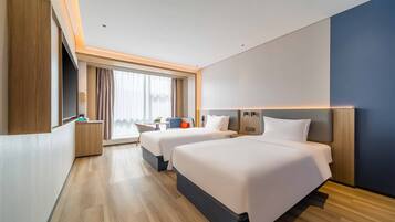 A hotel room with two beds, a TV, a desk, and a window with curtains.
