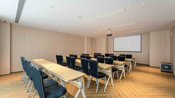A conference room with a long table, chairs, a projector screen, and a whiteboard.