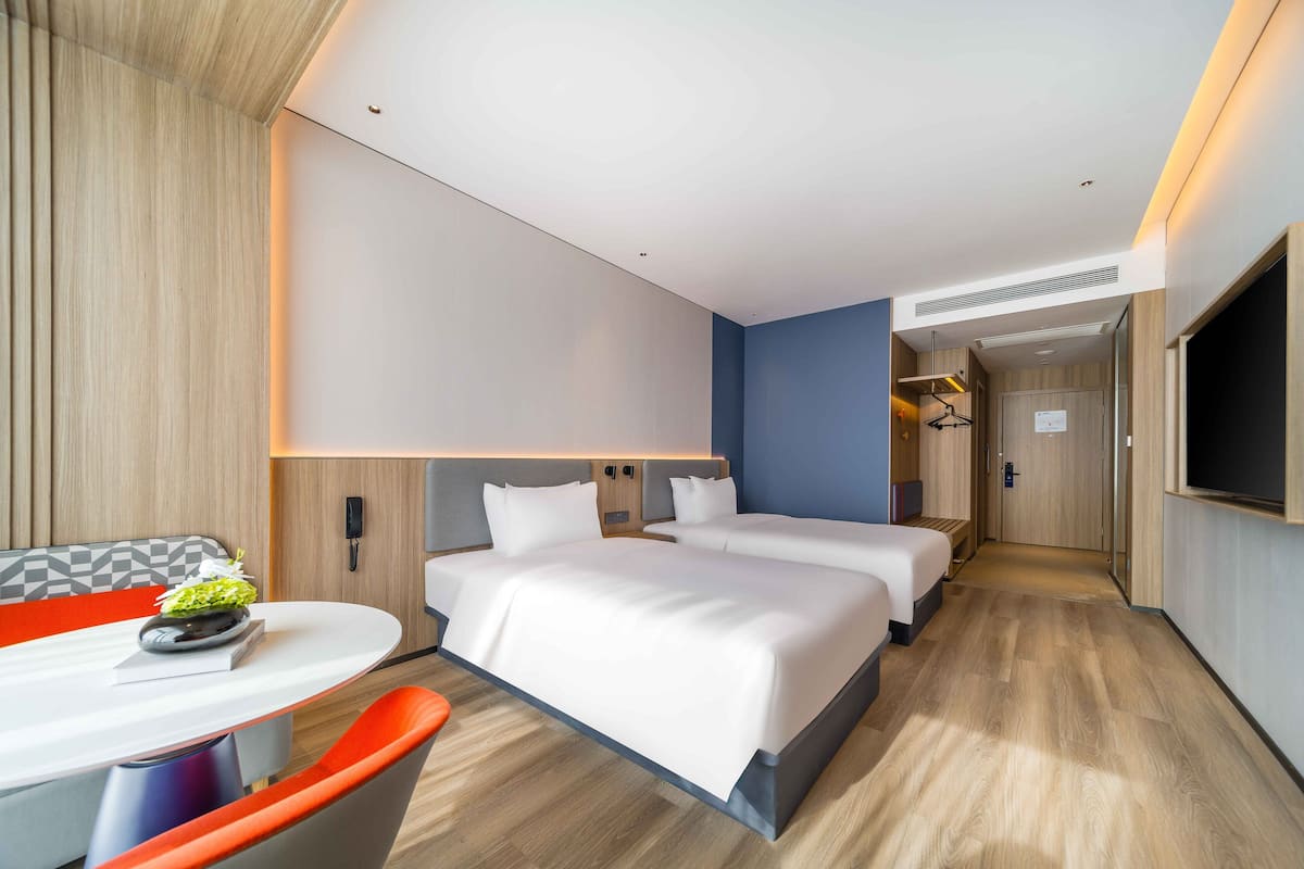 A modern hotel room with a large bed, a desk, and a TV.