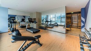 Un gimnasio moderno con cintas de correr, elípticas y pesas libres.