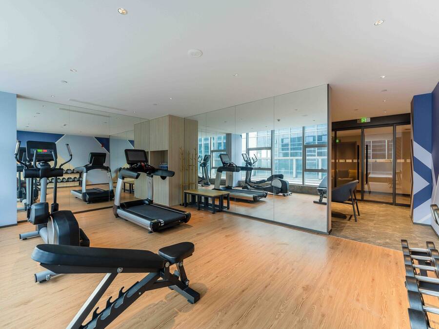 Un gimnasio moderno con cintas de correr, elípticas y pesas libres.