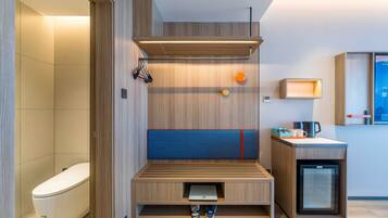 A modern bathroom with a built-in bench, a toilet, a sink, and a small refrigerator.