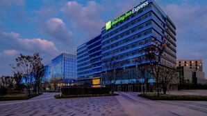 A multi-story Holiday Inn Express hotel with a modern glass facade and blue lighting accents.