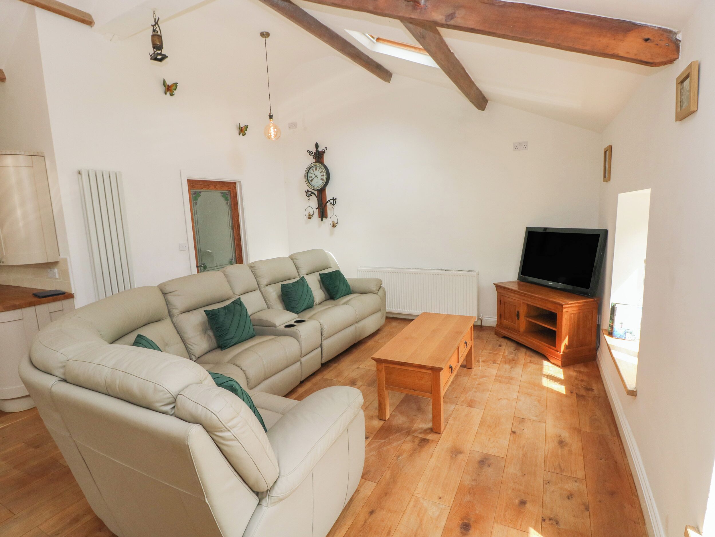 A living room with a sectional sofa, wooden coffee table, and a television on a wooden stand.