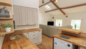 A modern kitchen with wooden countertops, white cabinets, and a built-in dishwasher. - Greenheart Cottage (Port Talbot)