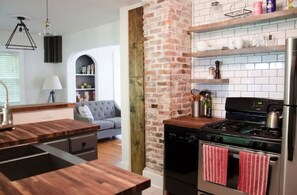 Enjoy cooking in this well-equipped kitchen with oven, stainless steel refrigerator, and wooden countertops.