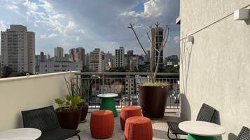 A rooftop terrace with outdoor seating, potted plants, and a city skyline view.