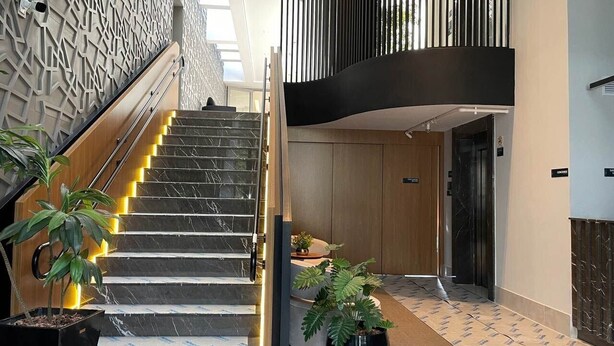 A modern hotel lobby with a marble staircase, potted plants, and a geometric wall design. - Studio ID Lisboa (São Paulo)