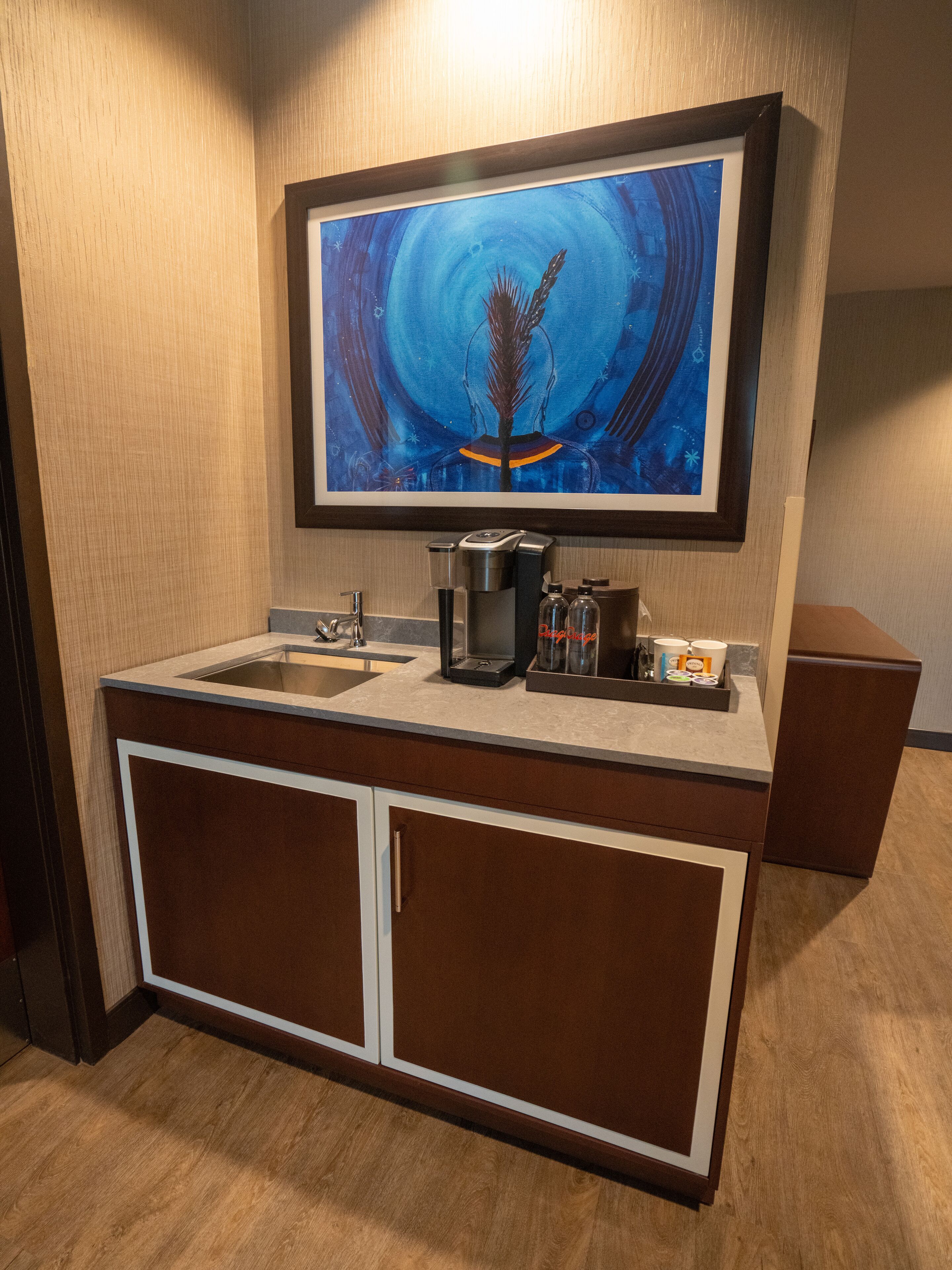 A modern bathroom with a large mirror, a sink, and a coffee maker.