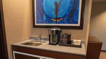Un baño moderno con un espejo grande, un lavabo y una cafetera.