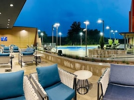 Un patio al aire libre con asientos y una piscina al anochecer.