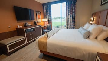 Ein Hotelzimmer mit einem großen Bett, einem Schreibtisch mit Computer, einem an der Wand befestigten Fernseher und Blick ins Freie durch die Fenster.