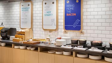 A breakfast buffet with signs indicating breakfast is included and ready when you are, and a sign promoting bacon.