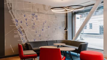 A modern lounge area with a large map on the wall, seating arrangements, and a view of the street outside.