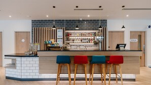 A modern bar area with a counter, stools, and a variety of bottles. - Holiday Inn Express Liverpool Central by IHG (Liverpool)