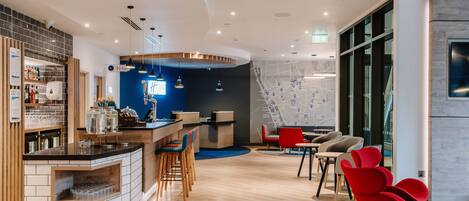 A modern hotel lobby with a bar area, seating, and a large map on the wall.