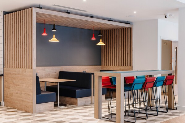 Un restaurante moderno con barra, mesas con cabinas y taburetes altos.