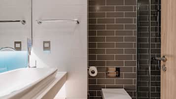 A bathroom with a bathtub, toilet, and shower area.