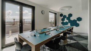 A conference room with a long table, chairs, a clock, and a view of the sea through large windows. - Holiday Inn Express Liverpool Central by IHG (Liverpool)