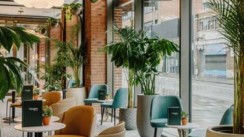 A modern indoor seating area with comfortable chairs, tables, and potted plants.