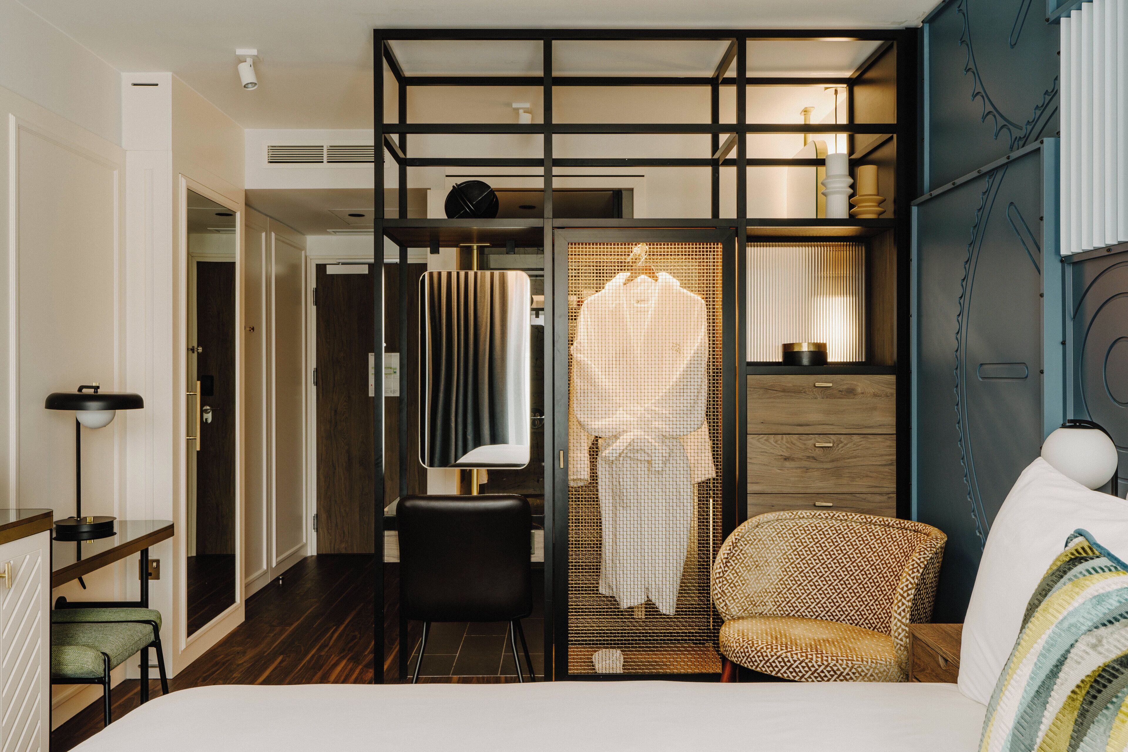 A hotel room with a bed, a chair, a desk, and a wardrobe.